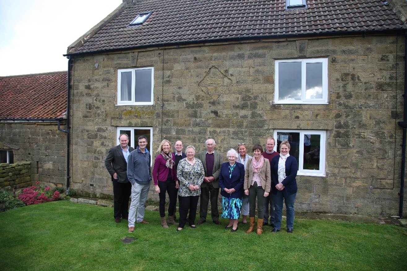 A group of people standing in front of a house
Description automatically generated